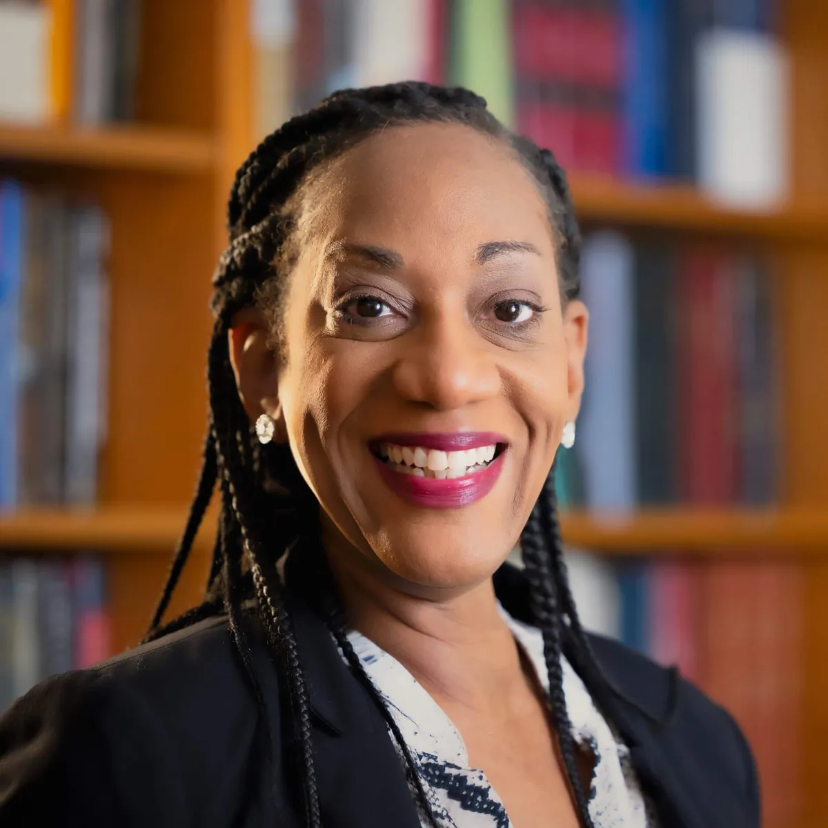 Kamilah Clark, Dean of Students, smiling in a blazer in front of a wall of law books.
